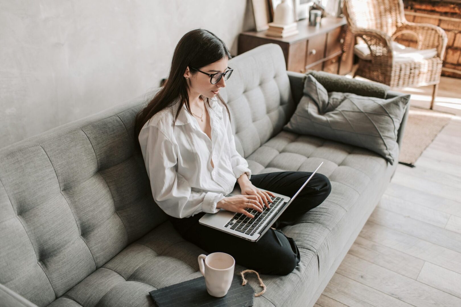 A woman sitting on the couch with her laptop.